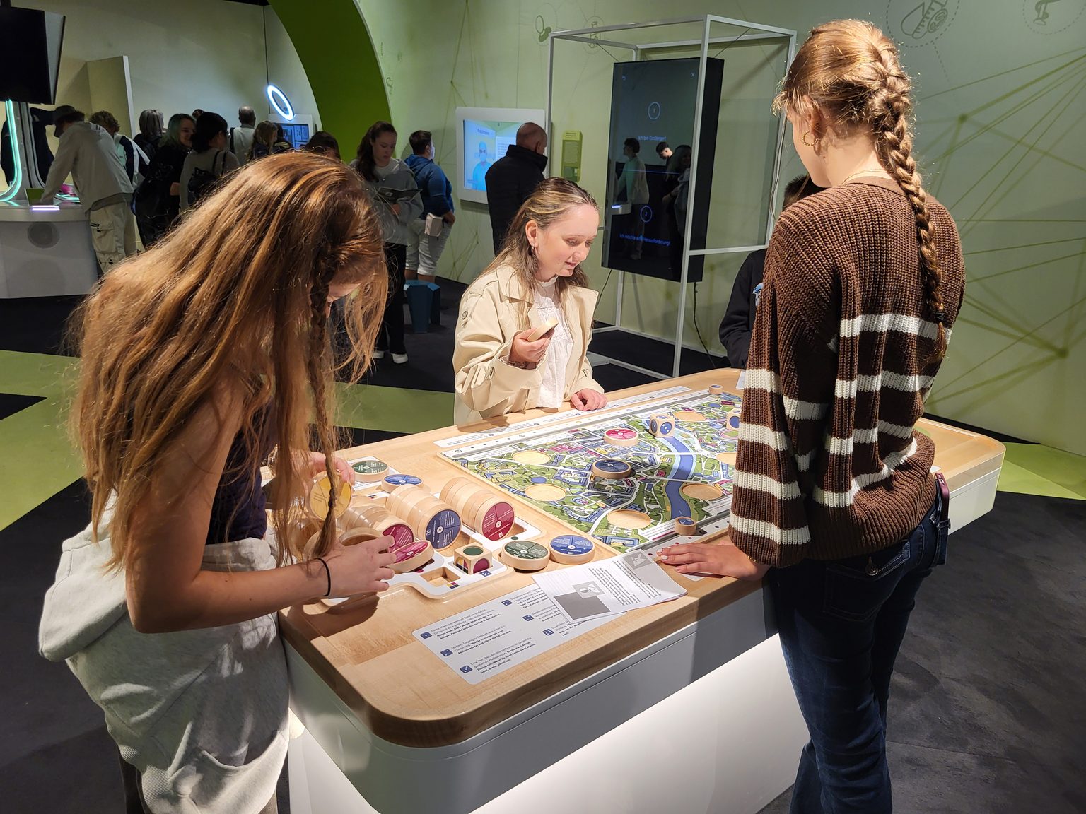 Ausstellung: Junge Leute untersuchen interaktives Spielbrett mit bunten Elementen
