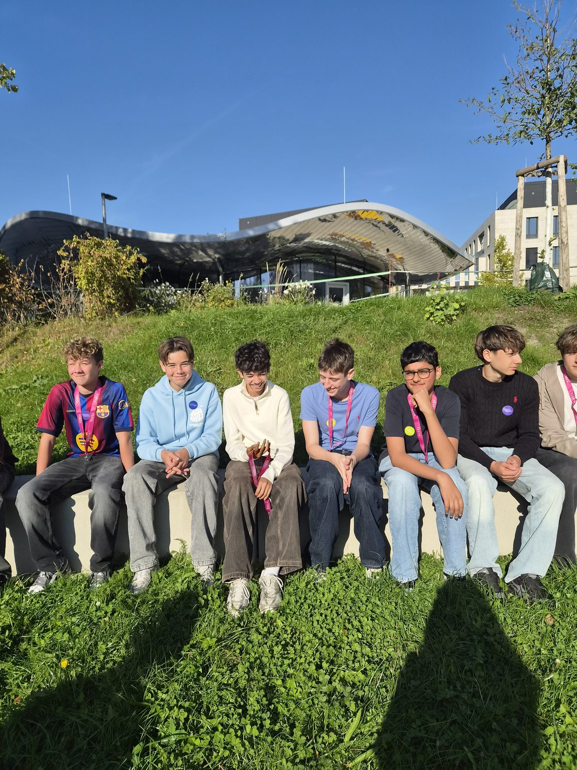 Jungs mit Medaillen sitzen vor einem modernen Gebäude in Linz