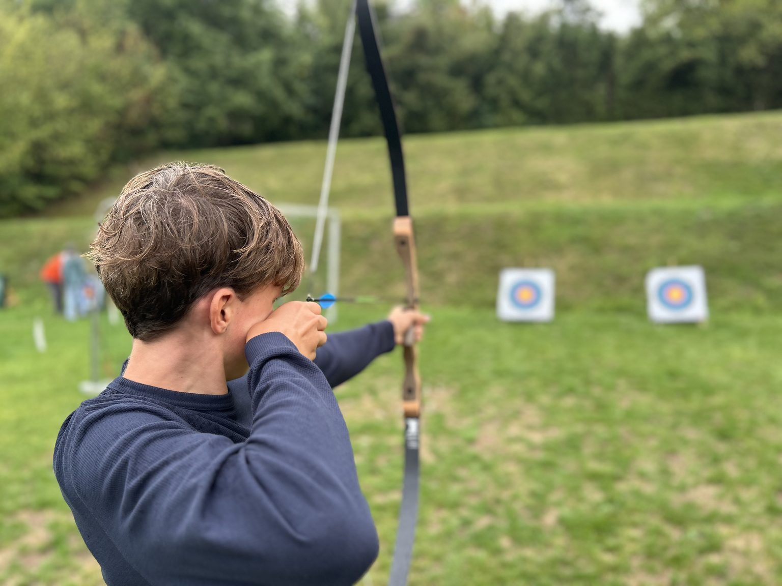 Bogensport-Schütze zielt auf Zielscheiben auf einer Wiese im Freien.